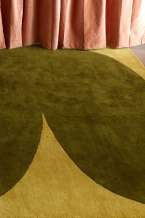 Pink curtains frame a green, hand tufted rug called Dove Rainforest by angela adams