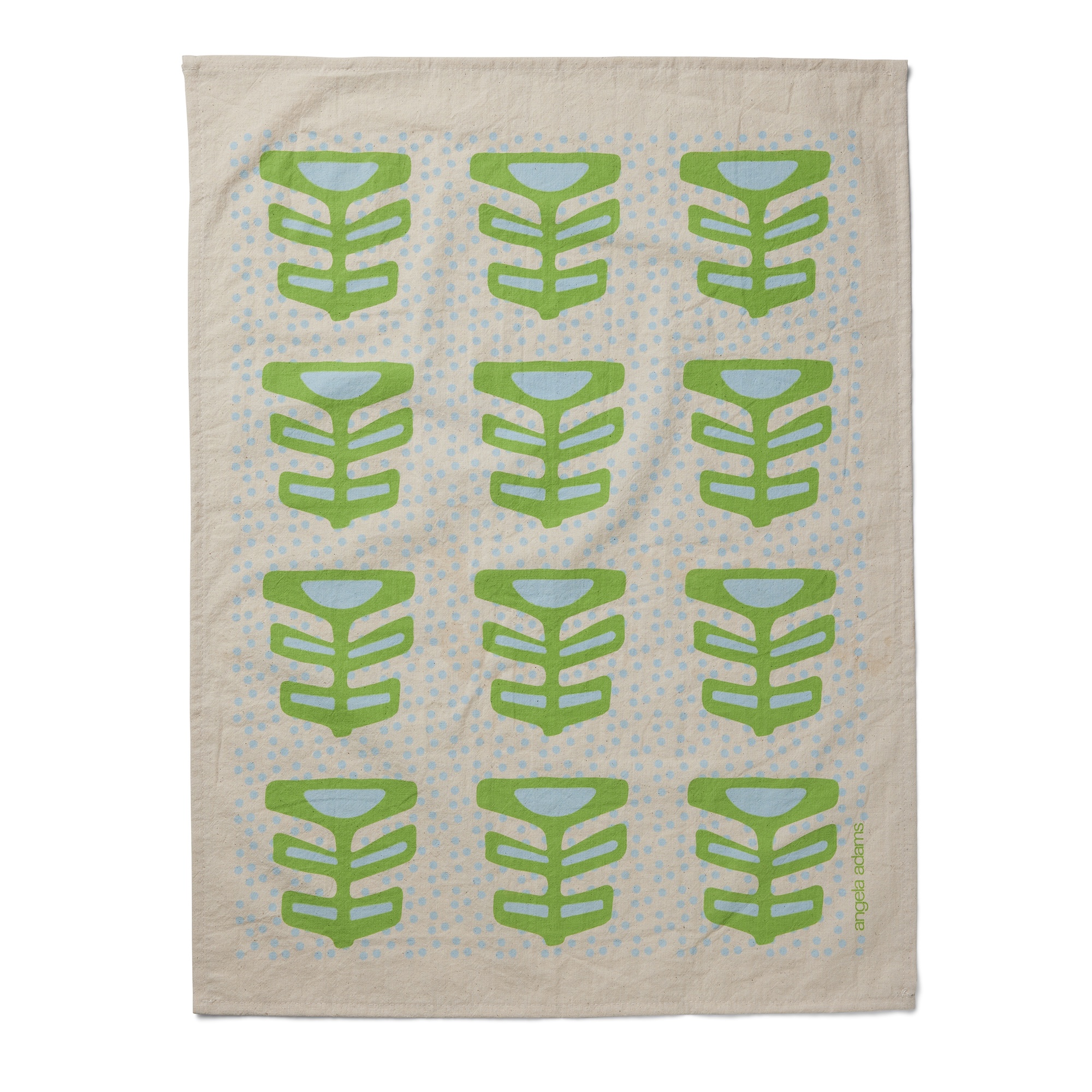 A light beige tea towel features a repeating pattern of twelve stylized green leaf or plant motifs, arranged in four rows of three. Each motif has a central stem with three pairs of leaves branching off, and a light blue semi-circular shape at the top. The background is subtly patterned with small, light blue, irregularly placed dots. "angela adams" is written vertically in small green letters on the right edge of the towel.