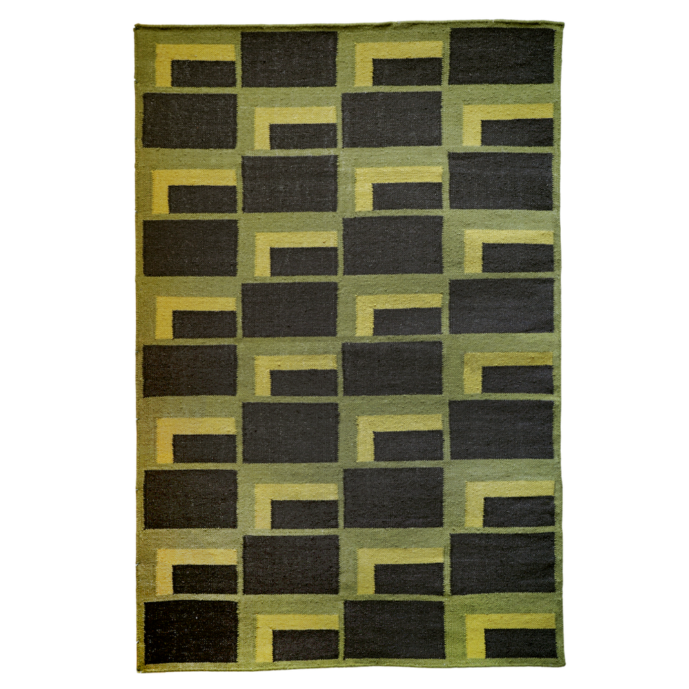 A rectangular woven rug featuring a geometric pattern of alternating dark charcoal and olive green shapes. The design is composed of a grid of rectangular blocks, each with an inner "L"-shaped motif in green wrapping around a smaller dark rectangle. The overall pattern is consistent and symmetrical, creating a bold, modern visual effect. The rug has a flat weave texture and slightly irregular edges, indicating a handcrafted appearance.