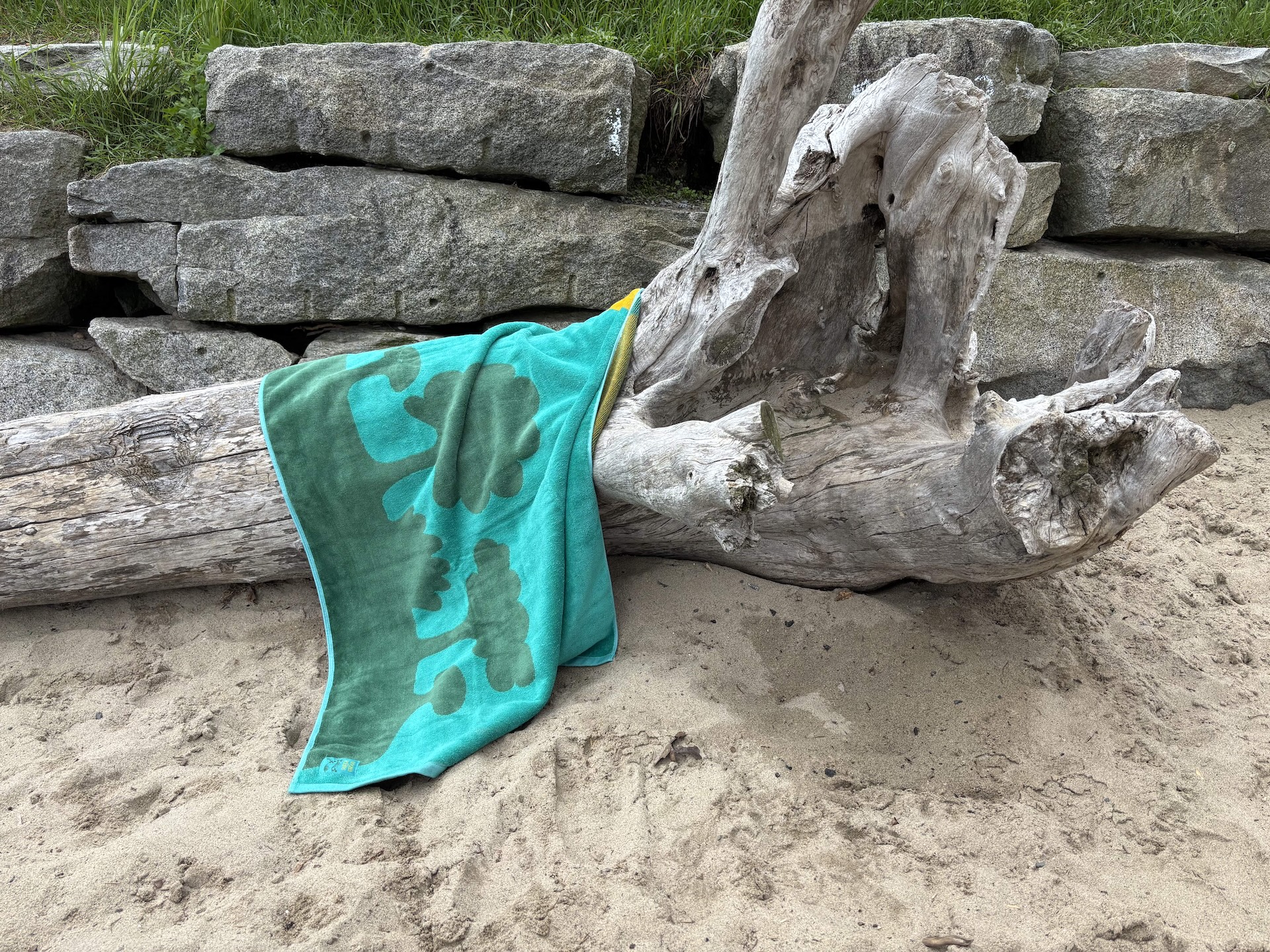 a photo of the island family beach towel hung over a piece of driftwood