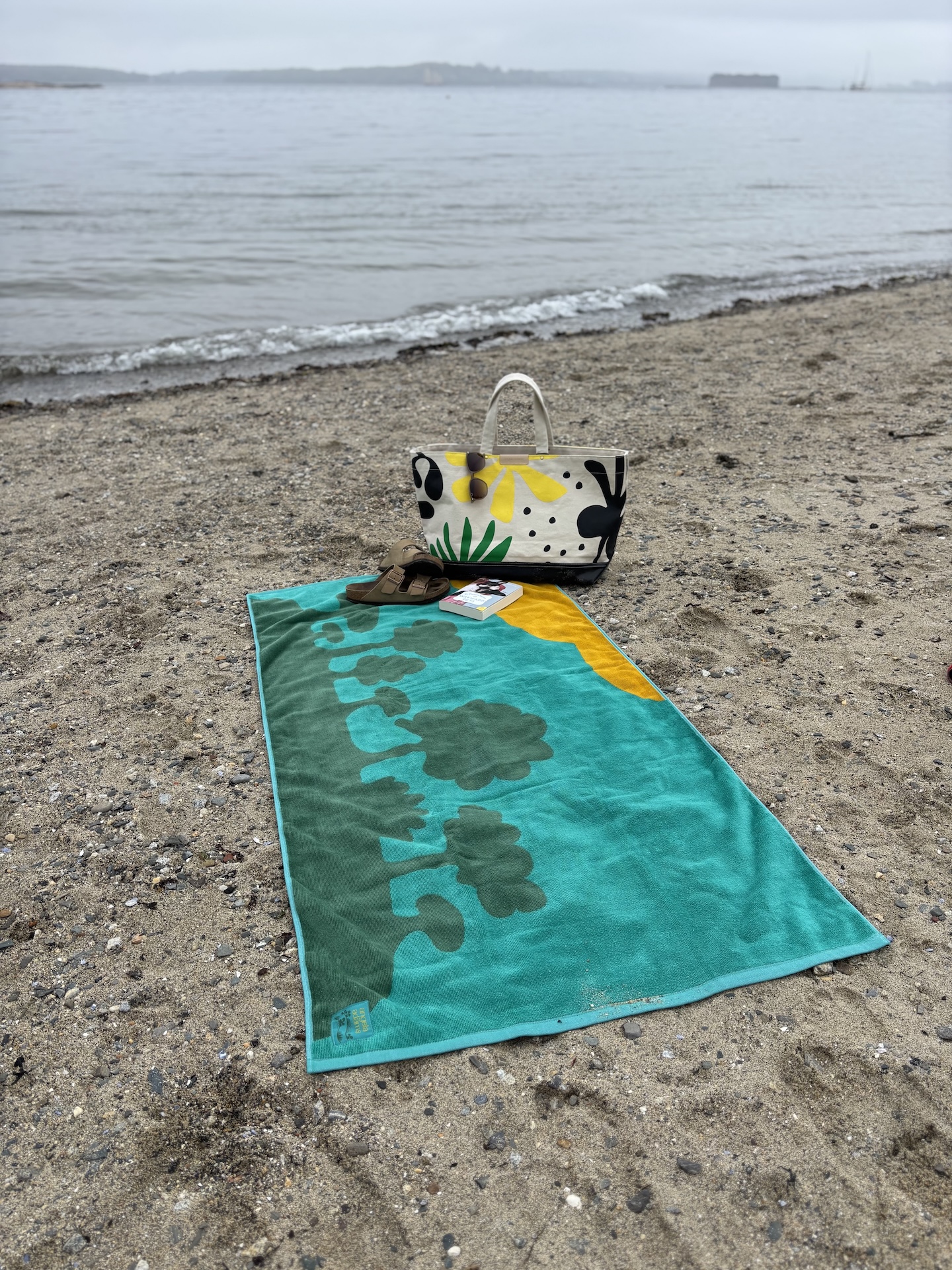 a picture of the island family beach towel with a tote bag, book and sandals on it laying on the beach