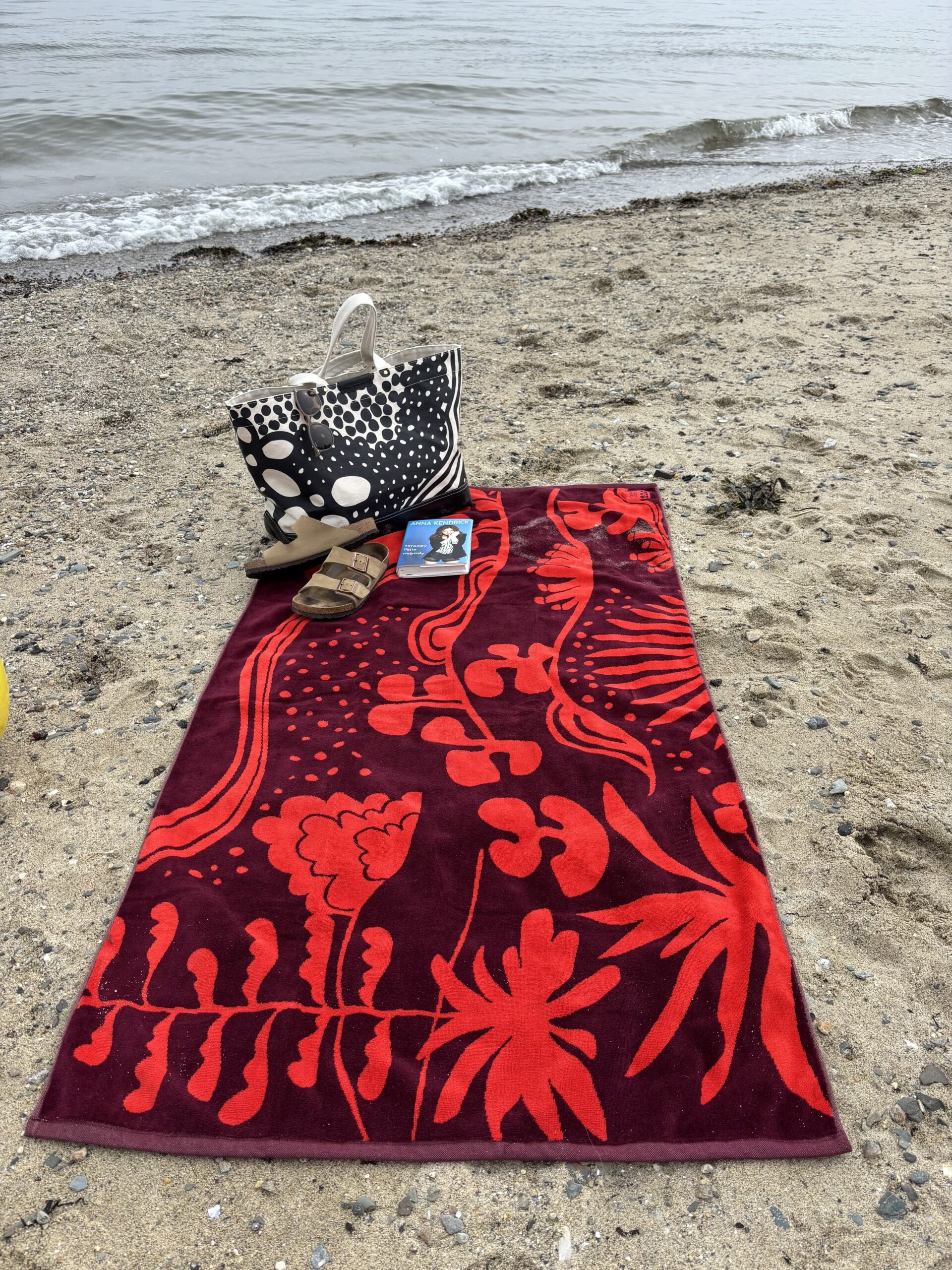 a photo of the agave beach towel laying on the sandy beach with the ocean behind it.