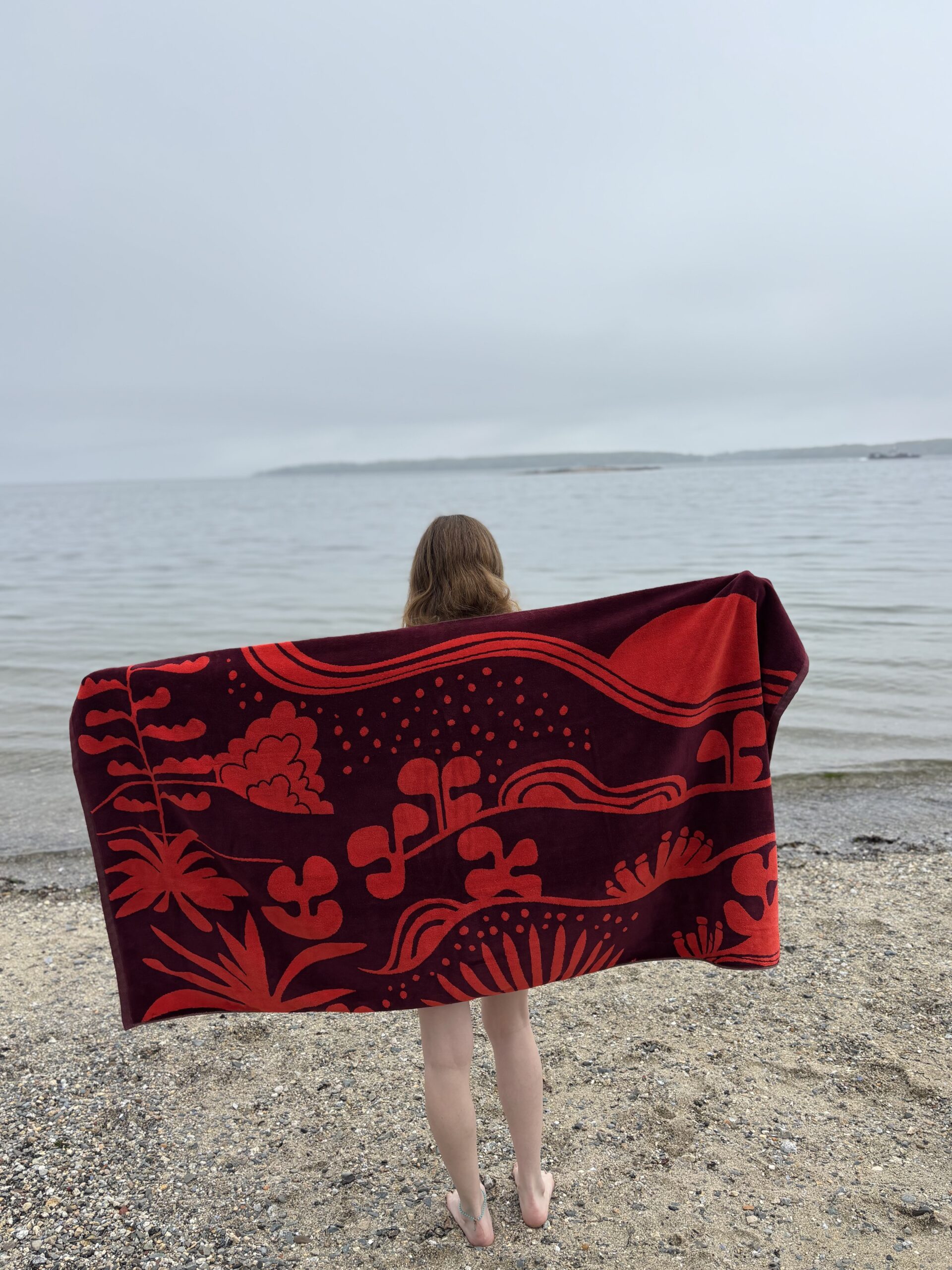 a picture of a girl holding the agave beach towel behind her on the beach