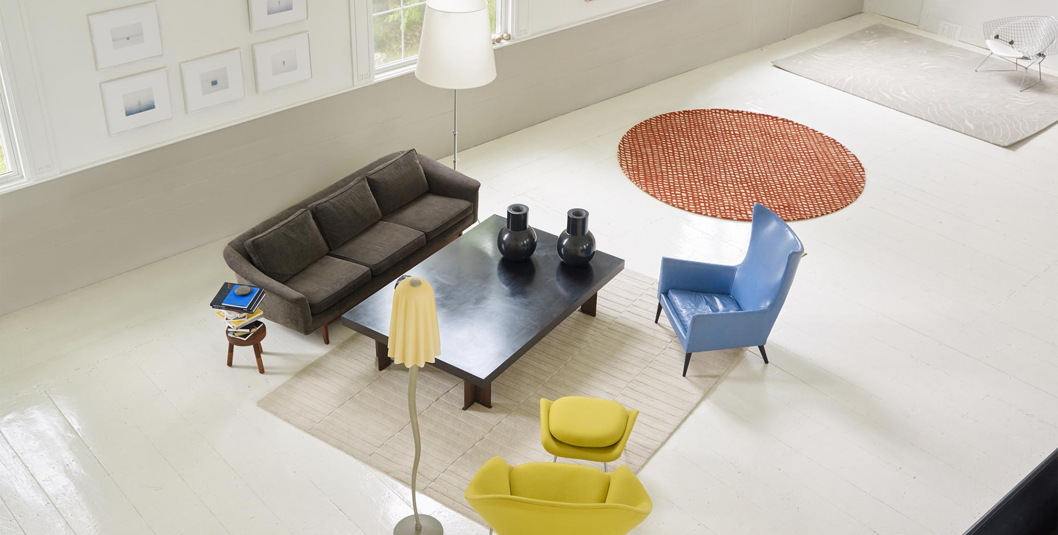 A beige and white neutral area rug surrounded by colorful modern den furniture in a large open room.