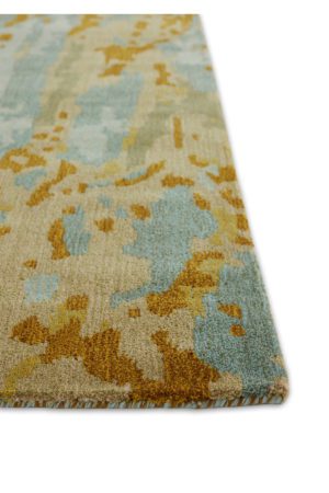 A corner of a plush, area rug with reds, and greens called Bark Aspen