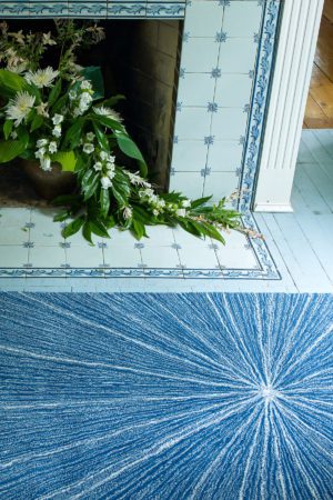 a blue angela adams Grace Sapphire rug in front of a fireplace