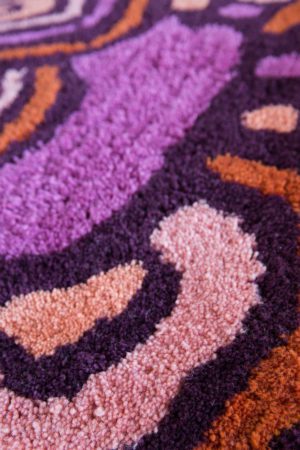 a detail of a red, and pink floral pattern, modern area rug called Maeve Tulip