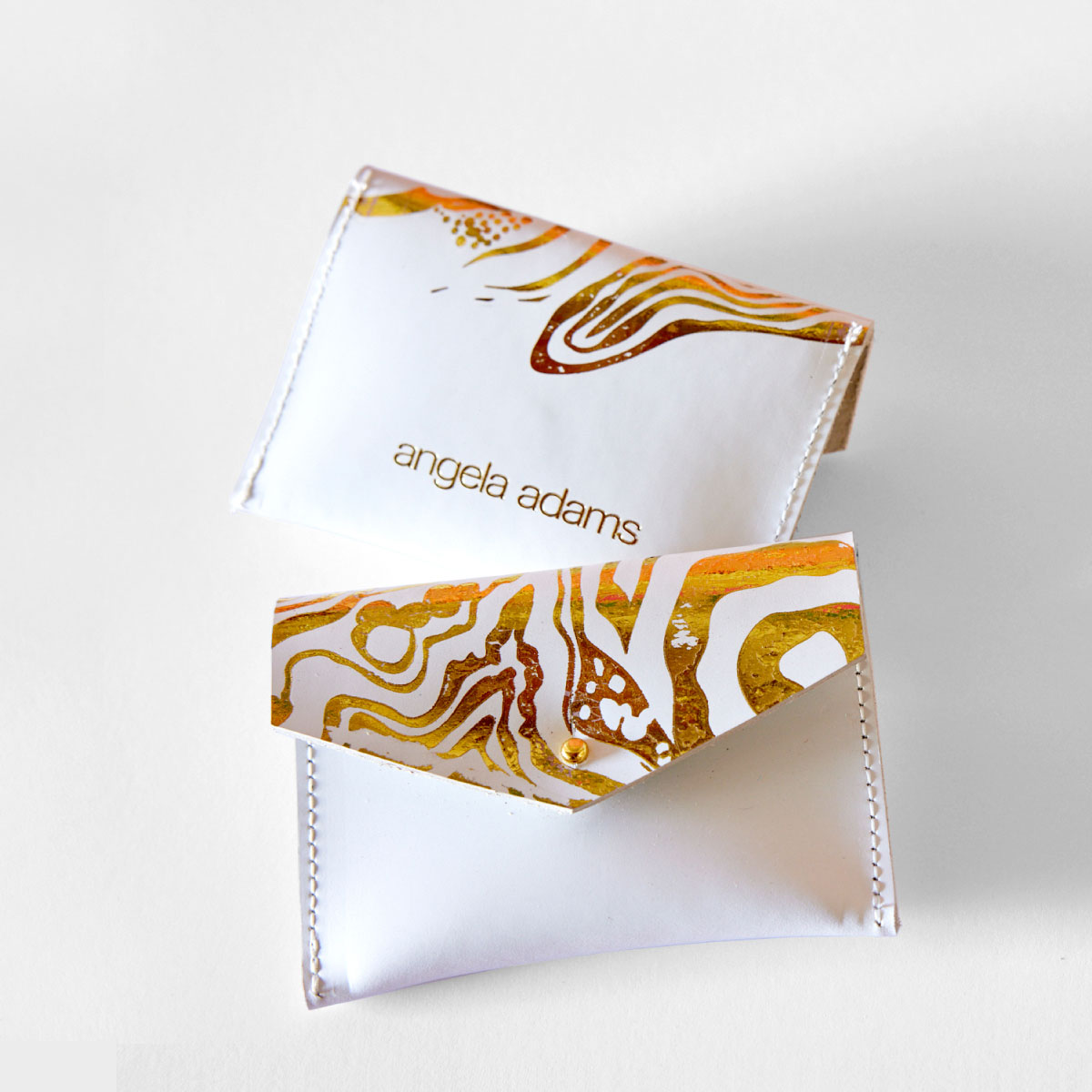 A white and gold, hand sewn, leather wallet called Nebula Cloud by Angela Adams.