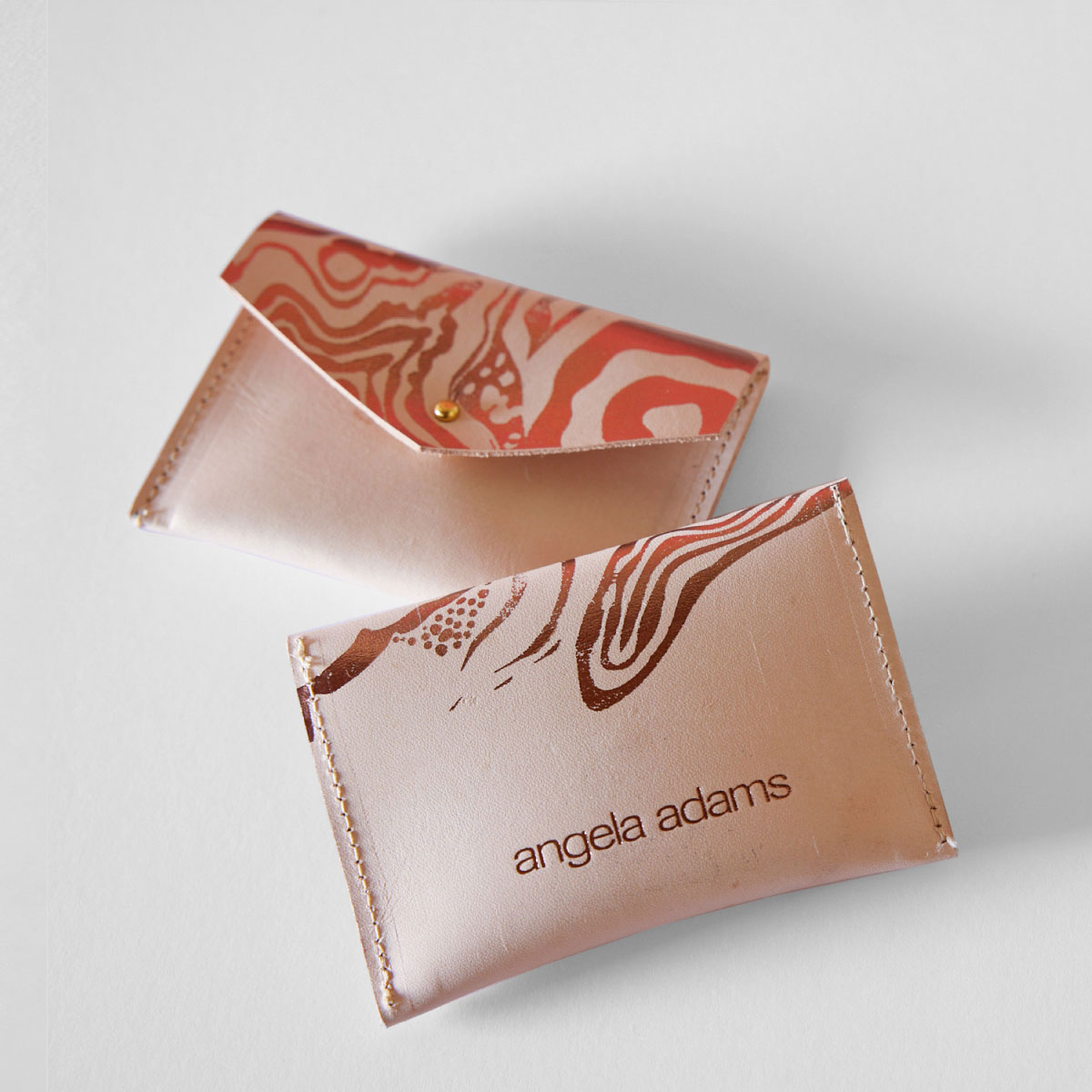 A shiny flesh colored, hand sewn, leather wallet called Nebula Nude by Angela Adams.