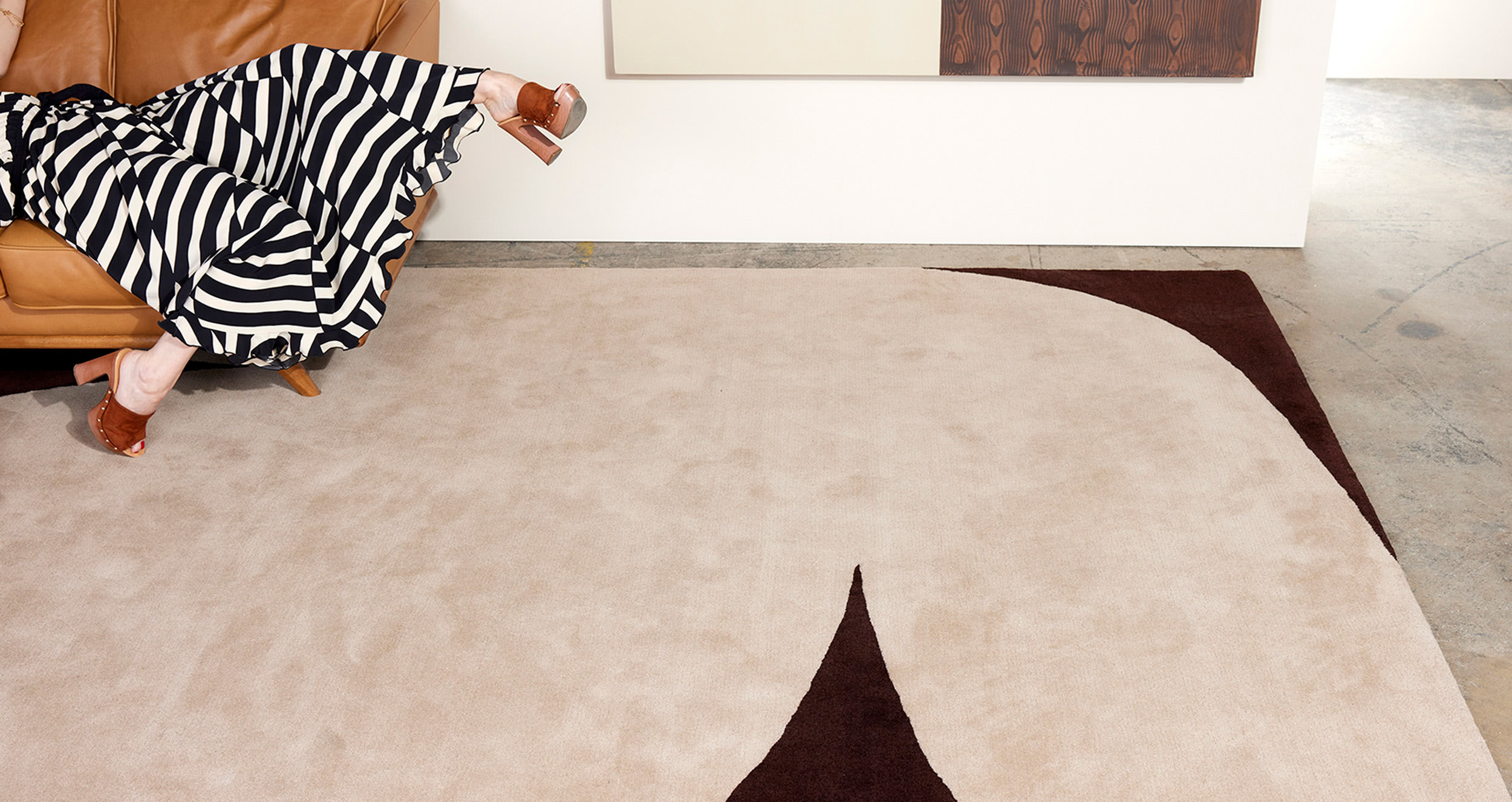 A woman in black and white drapes herself over a plush area rug called Dove Moonlight