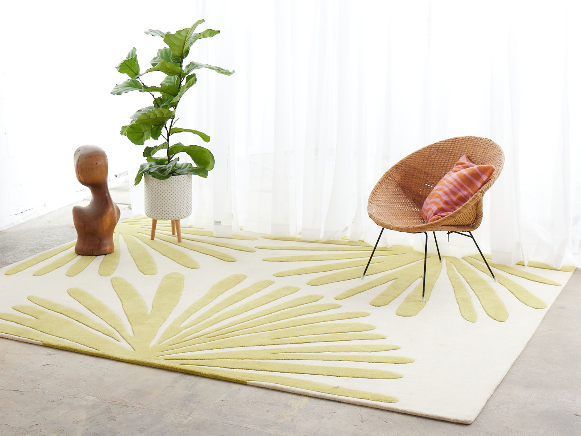 A bright room with wicker chair and modern area rug called Daisies Sunny by Angela Adams