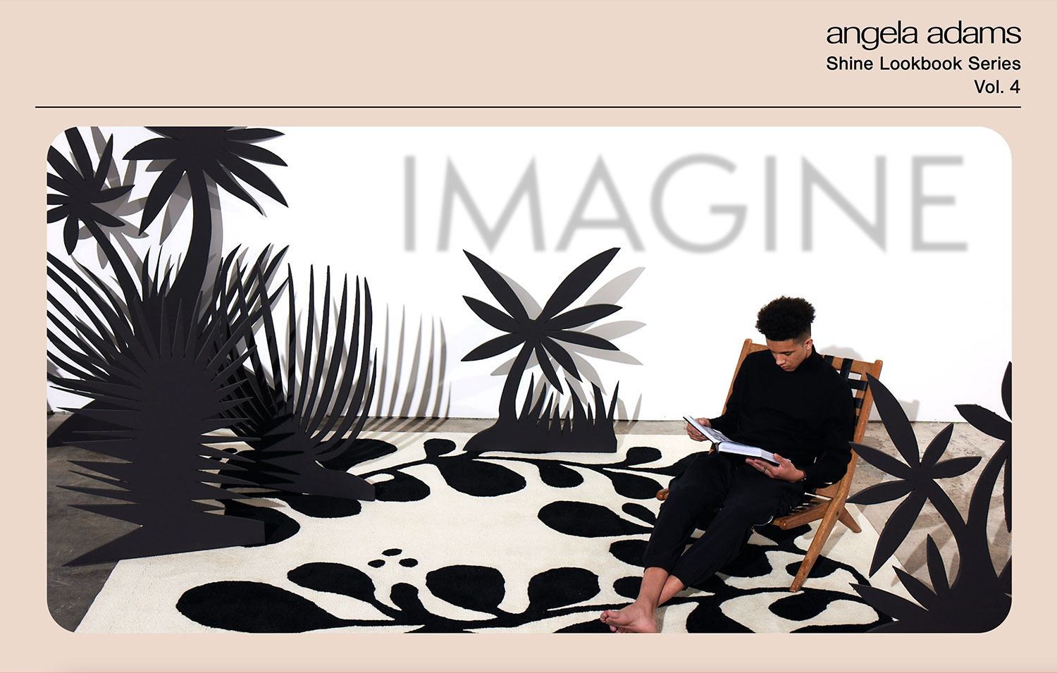 A young man sits reading surrounded by black and white life-size abstract tree and organic shapes.