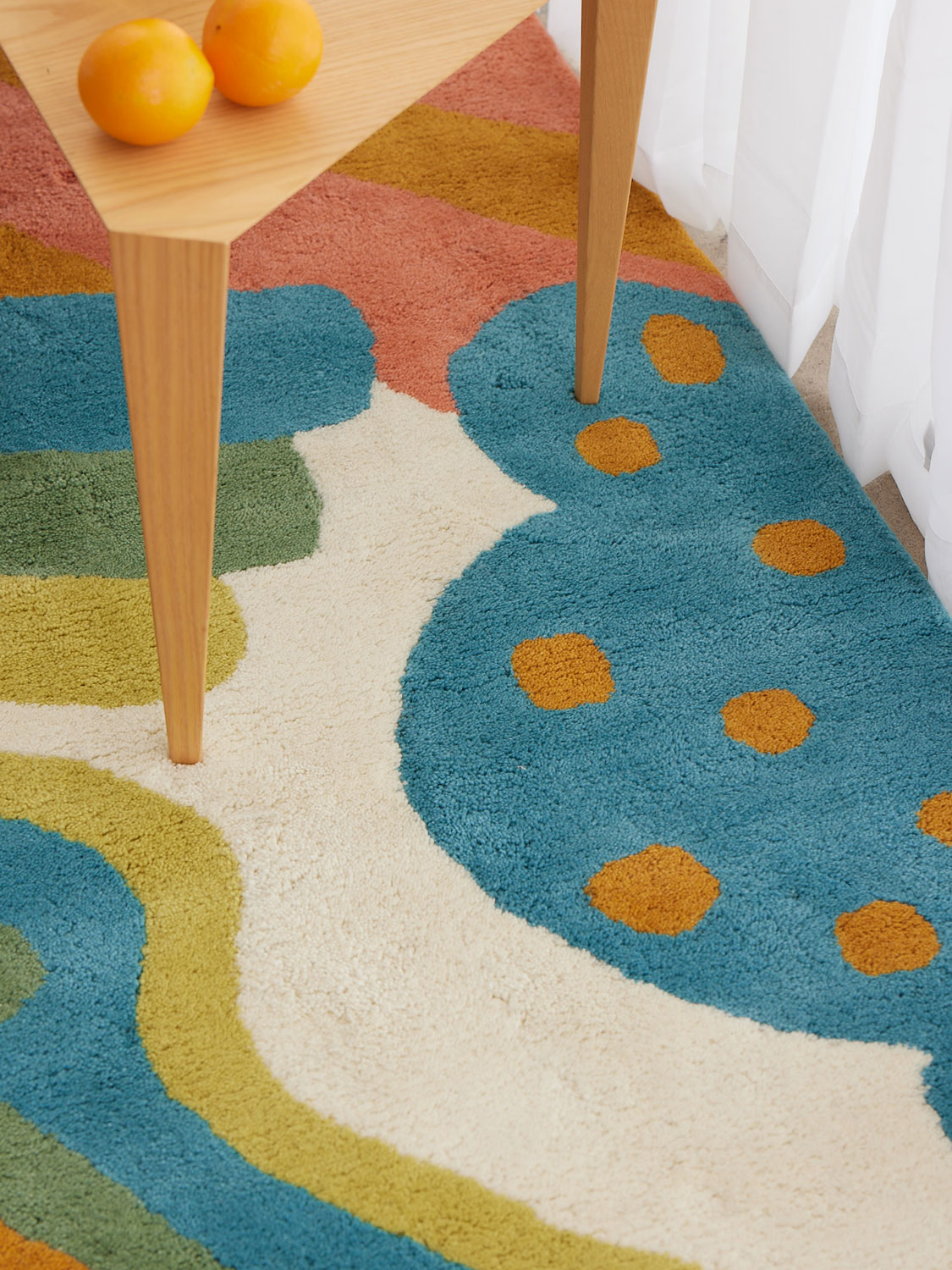 shine-angela-adams-daytrip-happy-hero-02 a wooden table on a multi-colored, modern area rug by Angela Adams called Daytrip Happy